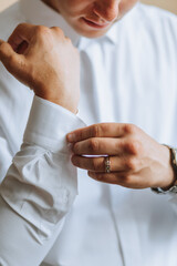 Morning of the groom and details, white shirt, good light, young man, stylish groom getting dressed, getting ready for the wedding ceremony. close-up of male hands