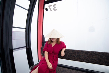 A woman tourist is staying on cable car while traveling on Bana Hill in Danang, Vietnam.