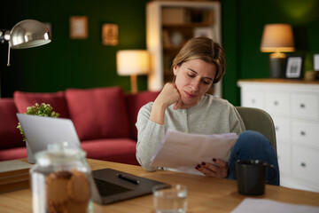 Mid adult woman examining her bank statement at home office
