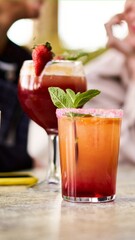Two glasses of Natural cocktails or Mocktails on a table surrounded by a group of unrecognisable female friends gathering outside a bar in a terrace. Copy space image.