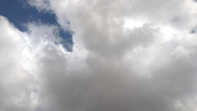 Giant whitish cumulus clouds move across the sky in the morning