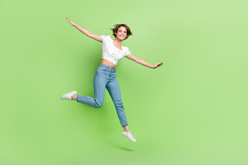Fototapeta na wymiar Full length portrait of overjoyed pretty person jumping good mood empty space ad isolated on green color background