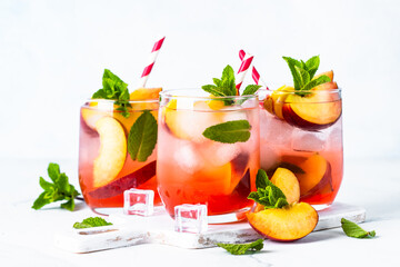 Peach cocktail, iced peach tea, fruit drink with fresh fruits and mint.