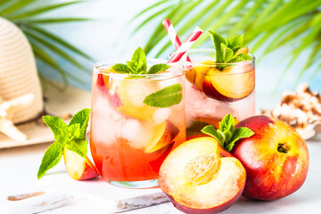 Fototapeta premium Peach cocktail, iced peach tea, fruit drink at tropical background with palm leaves.