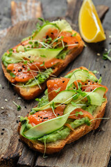 Open sandwiches with salted salmon, guacamole avocado and fresh greens. Delicious breakfast or snack, Clean eating, dieting, vegan food concept. top view.