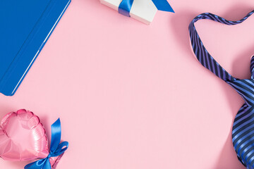 Father's day concept. Flat lay top view of tie, gift box, blue notepad, hearts on pastel pink...