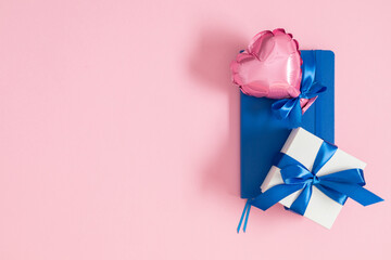 Father's day concept. Flat lay top view of tie, gift box, blue notepad, hearts on pastel pink background with place for text, promotional and  greeting message