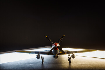 Scale model of the airplane fighter on a dark background with a side light. Toy.