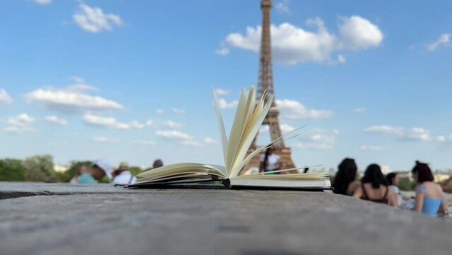 Wind Flipping Notebook Pages Eiffel tower on background