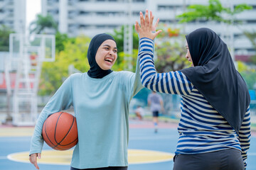 Young asian muslim girl teen wearing hijab going to play basketball on the outdoor court in the...