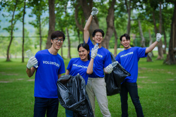 Volunteers of various nationalities are showing solidarity, donating their personal time, holding black trash bags to collect plastic waste for recycling to reduce pollution in a public park.