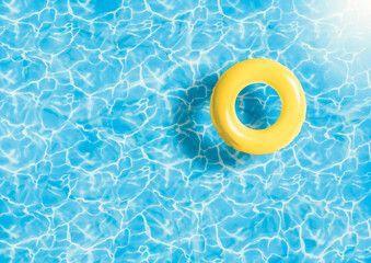 Yellow swimming pool ring floating in blue water. Summer colors concept. Vacation and summer holidays in swimming pool. Relaxing background