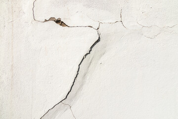 A house white wall with a large crack. Grunge concrete cement white wall with a crack in an...