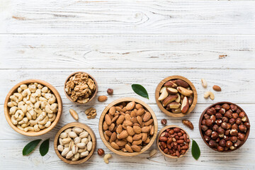mixed nuts in wooden bowl. Mix of various nuts on colored background. pistachios, cashews, walnuts, hazelnuts, peanuts and brazil nuts - obrazy, fototapety, plakaty