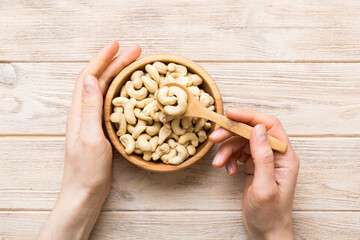 Woman hands holding a wooden bowl with cashew nuts. Healthy food and snack. Vegetarian snacks of different nuts
