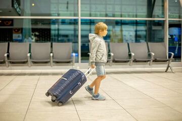 Fototapeta na wymiar Children with suitcases at airport, walking at night for a flight