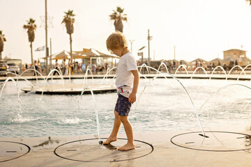 Cute child, boy, playing with water in fountain in Tel Aviv