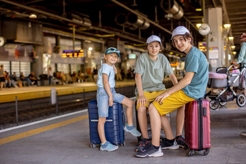 Children, boy brothers holding suitcases, travelin, waiting at trainstation to go to the airport