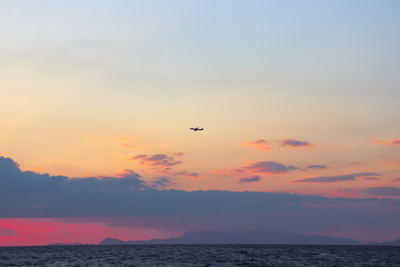 Single plane flying through the clouds at sunset at Paralia Ixia beach off Rhodes city 