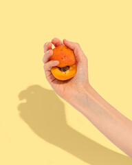 An apricot cut in half in a woman's hand