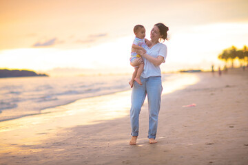 Mother and baby on tropical beach at sunset.