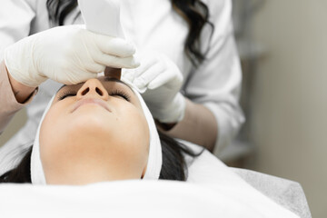 Obraz na płótnie Canvas Individual approach to the skin: a professional cosmetologist takes into account the unique needs of the patient's skin, using ultrasonic facial cleansing as an individual approach to facial skin care
