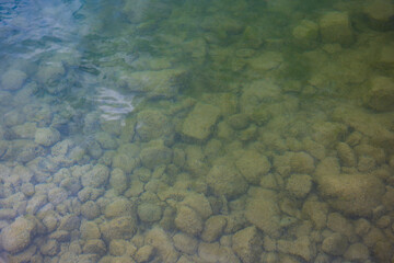 Moss covered rocks under cloudy river water. Top view, no people