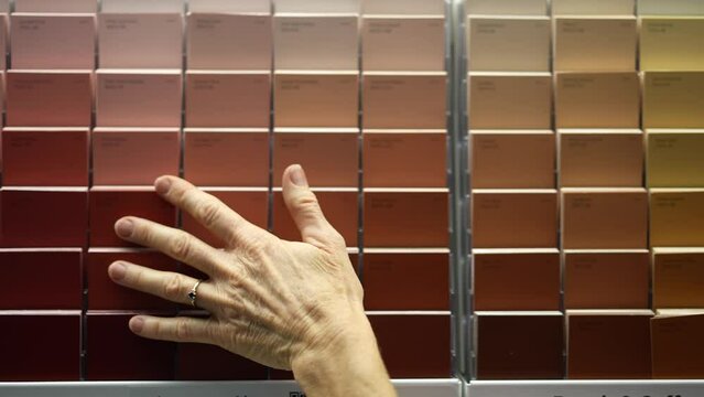 Closeup of womans hands looking at paint chips in a hardware store. Concept of home remodeling shopping experience.