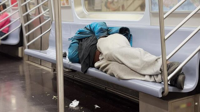 A homeless man sleeps in a Manhattan subway car.  	