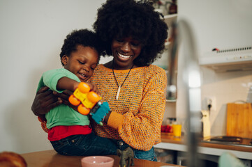 A happy interracial family is playing with toys in a kitchen at home.