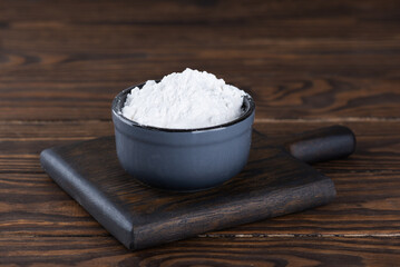White tapioca starch powder in a bowl on a wooden table, dry cassava root.