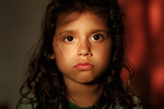 Close-up portrait of a charming 5 year old girl. The child looks sadly at the camera. girl with dark eyes and hair