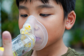 Cute Asian boy with asthma using inhaler and spacer,Inhaler, spacer and mask - obrazy, fototapety, plakaty