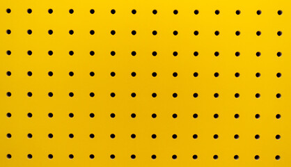 Yellow plastic perforated panel texture. Seamless tile abstract background. Pegboard.
