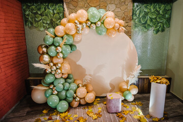 Reception at birthday party. Arch decorated green, brown, golden balloons, dry autumn leaves for...