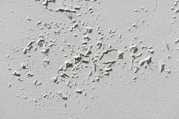 Cracked white paint on a flat plastered surface. Close-up.
