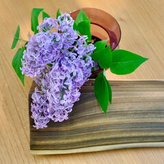 Overhead view of lilac flowers in vase next to block of ebony.