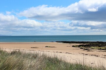 A beautiful view of the sandy coastline along the scottish coastline of Dornoch, in the highlands of Scotland.  It is a sunny day with blue sky.