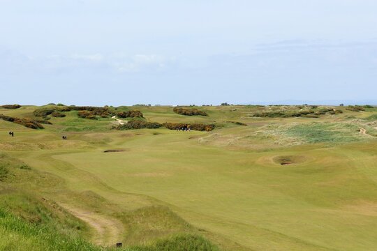 An incredible view of a classic links golf hole with pot bunkers in Scotland with the ocean in nearby outside of St. Andrews, Scotland