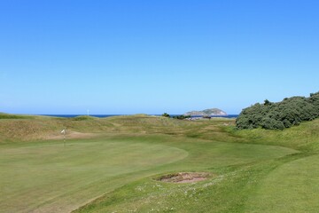 Fototapeta na wymiar An incredible view of a golf hole in Scotland with the ocean in the background in North Berwick, East Lothian, Scotland