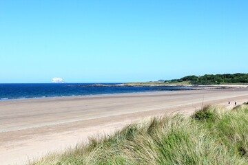 A beautiful view of the sandy coastline along the scottish coastline of North Berwick, East Lothian, Scotland.  It is a sunny day with blue sky