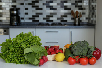 Kitchen table with groceries. Bunch of different raw organic fruits, vegetables, berries and greens lying in pile on a counter. Close up, copy space for text, interior background.