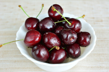 cherries with water drops isolated in white bowl, close up