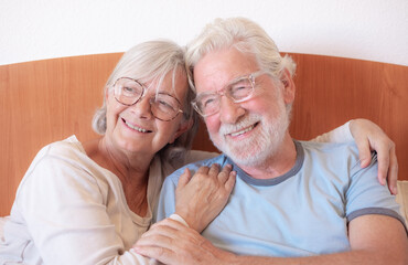 Love lives forever! Senior couple portrait hugging at home. Handsome old man and attractive old woman are enjoying spending time together while lying in bed.