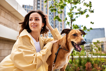 Charming young smiling girl with a dog of golden color while walking outdoors on a sunny day. The...