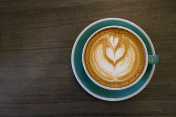 Cup of hot latte art coffee on wooden table.