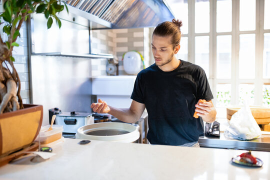 Young man standing and picking rice roll for nigiri sushi