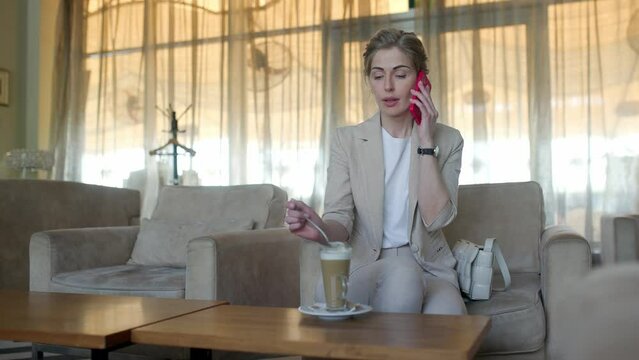 Young woman in cafe works with a smartphone. girl in a cafe uses a tablet and drinks delicious aromatic coffee. woman chatting, drinking coffee and relaxing. close-up.