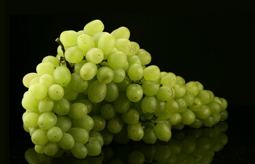 Bunch of white grapes with water drops on black background