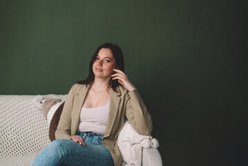 Happy beautiful young smiling woman sitting on sofa. Concept of wellbeing and self-care. Copy space